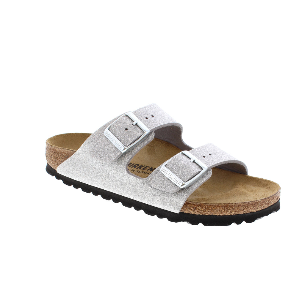 The Birkenstock Arizona in Glitter Silver combines decades of heritage with contemporary sparkle. This iconic two-strap sandal features a synthetic upper with a shimmering finish, delivering refined elegance without compromising the legendary comfort that made it a global staple.