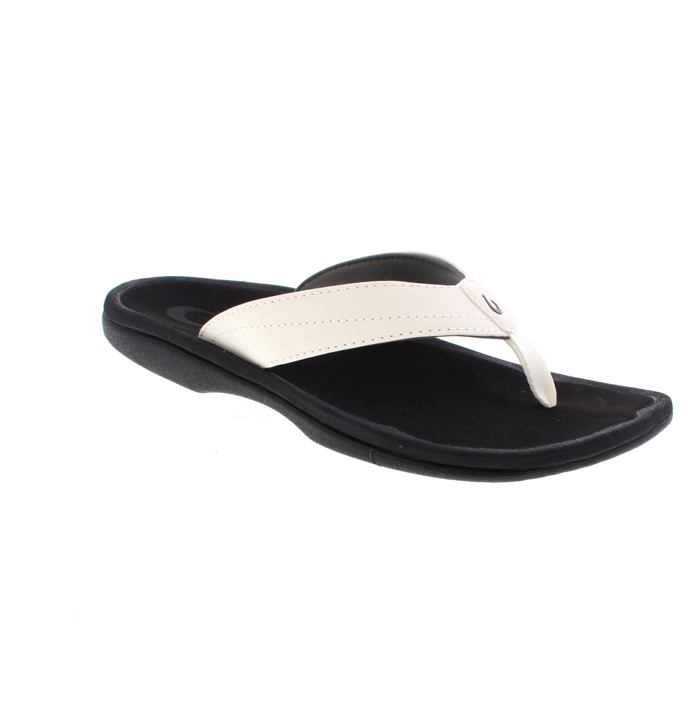 OluKai Ohana women's flip-flop 20110-WB40 in white and black. Features water-resistant man-made leather upper with soft microfiber lining. Slip-on style with light arch support keeps feet comfortable throughout the day. EVA/PU midsole and footbed paired with durable non-marking rubber outsole.