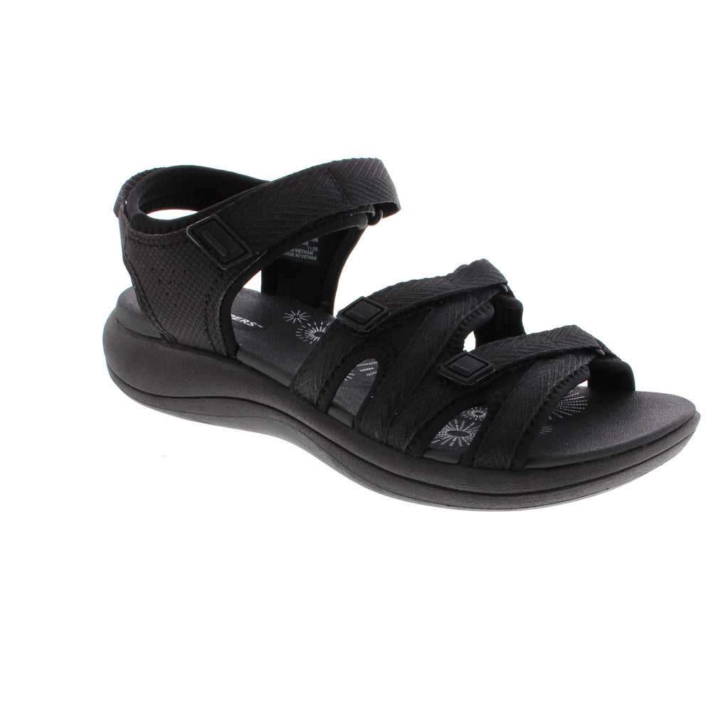 The Clarks Mira Madi is a black sandal combining leather and fabric with a velcro closure for easy on-and-off wear. It offers light arch support, shock absorption, and a cushioned microfiber footbed. Available in multiple widths and true to size.