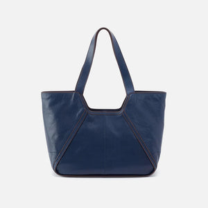 The Hobo Bags Bellamy Tote in Navy is the perfect blend of fashion and practicality. Its structured design allows for easy organization, while its versatile style transitions seamlessly from the office to weekend outings. Elevate your everyday look with this functional and stylish tote.