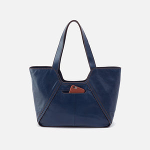 The Hobo Bags Bellamy Tote in Navy is the perfect blend of fashion and practicality. Its structured design allows for easy organization, while its versatile style transitions seamlessly from the office to weekend outings. Elevate your everyday look with this functional and stylish tote.