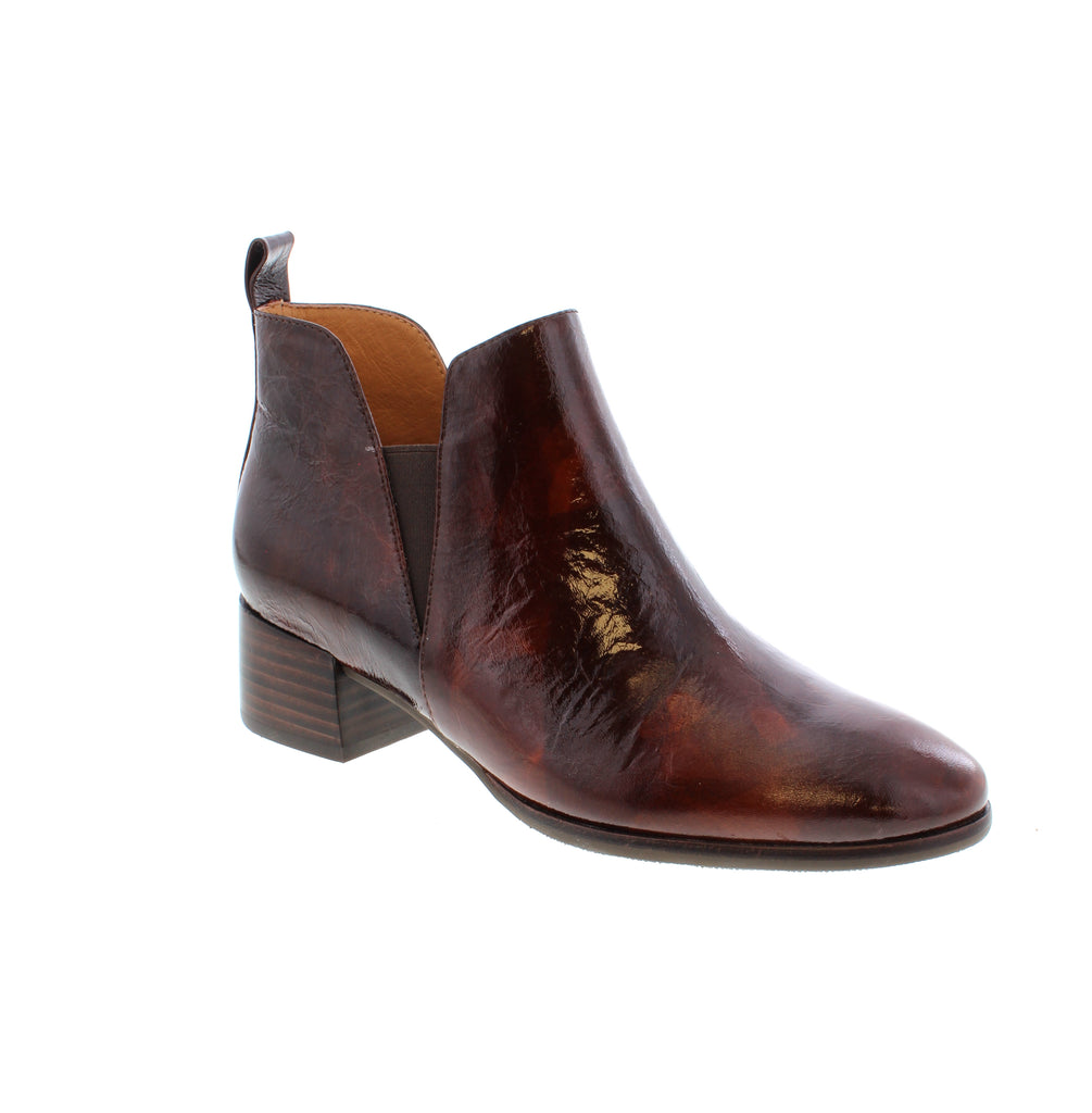 The Tamara London Anexia is a patent-leather ankle boot, featuring elastic gore panels for effortless on/off and a chunky heel for a touch of elegance.