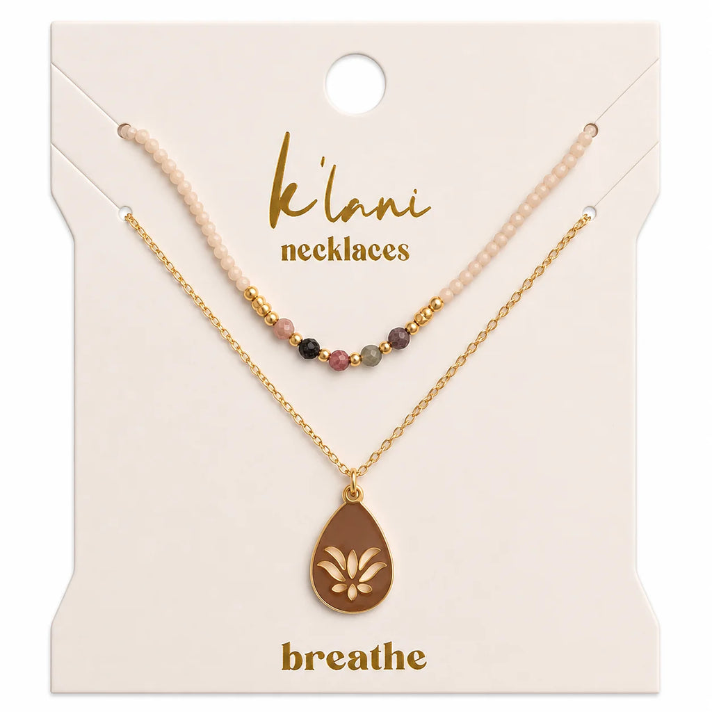 The K'lani Breathe Necklaces are a two-piece set designed for everyday elegance. The first necklace features blush and earthy stone beads, while the second showcases a gold-plated teardrop charm with a lotus flower detail. Together, they create a grounded, natural look that reminds you to stay rooted and bloom with grace.
