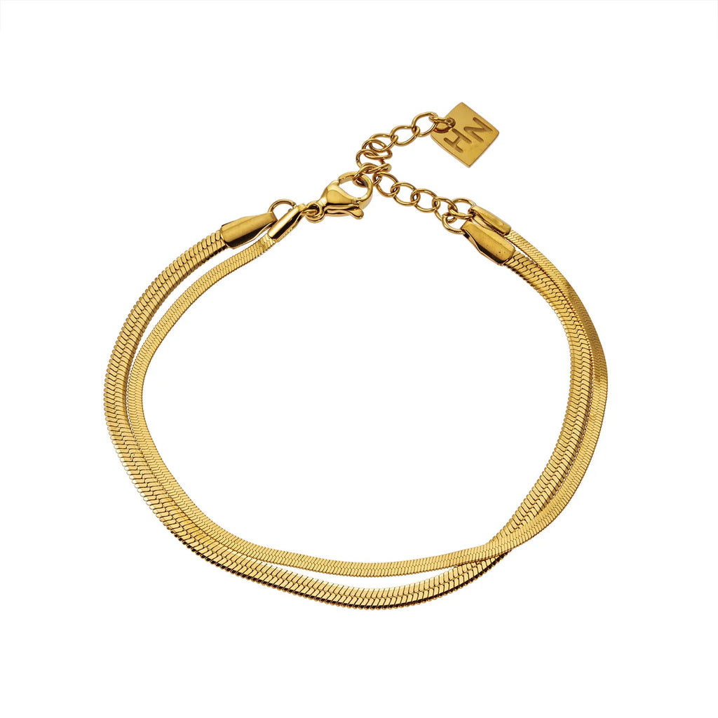 Elevate your everyday look with the Hackney Nine Inese bracelet. This sophisticated two-layer bracelet features contrasting widths and a captivating snake-skin texture that catches the light beautifully. Crafted with 18 karat infused gold, it delivers luxury without the worry—hypoallergenic, nickel-free, and built to last without tarnishing.