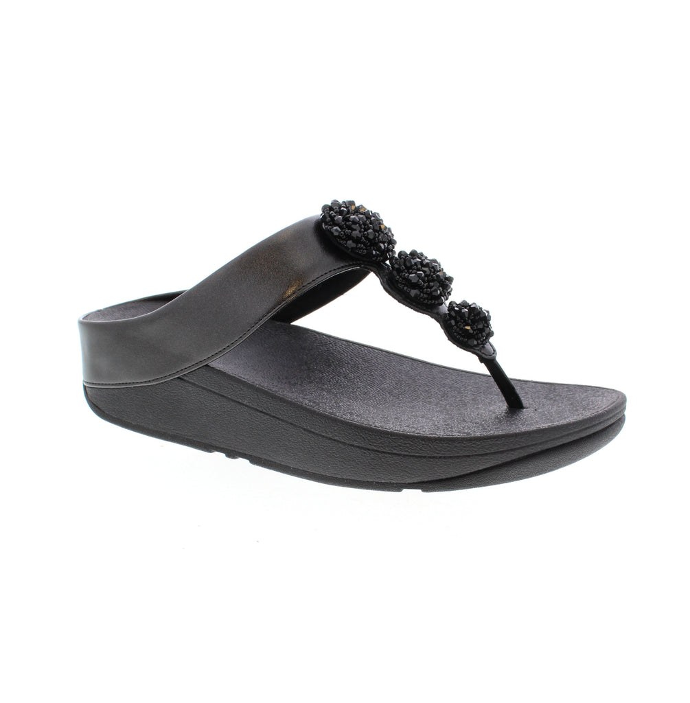 Step into effortless comfort with the FitFlop Fino Beaded Toe-Post Sandal in Metallic Black. Crafted from premium man-made leather, this thong-style sandal features an elegant beaded toe detail and rounded toe shape for a refined summer look. The cushioned EVA/PU footbed and foam midsole work together to provide all-day support. Perfect for casual warm-weather wear, this versatile sandal transitions seamlessly from poolside to everyday outings.