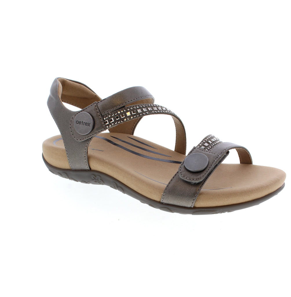 The Aetrex Jess pewter sandal offers reliable arch support and pronation control in a casual summer style. Its microfiber footbed features anti-bacterial and odor-control properties, while the padded collar and velcro closure ensure a secure, adjustable fit. Crafted with a leather upper and cushioned foam midsole, it's designed for narrow to medium feet and provides bunion relief. True-to-size fit for everyday comfort.