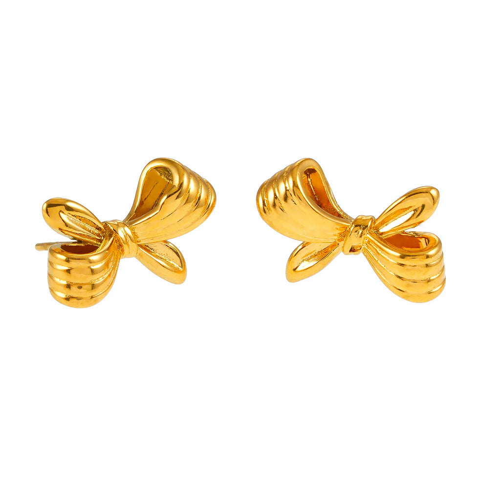 Elevate your style with the Hackney Nine Misty - Gold Bow Stud Earrings. Featuring a delicate bow design with textured detailing and polished edges, these earrings add a refined touch to any outfit. Their lightweight and secure butterfly back make them perfect for all-day wear.