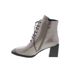 Make a statement with the Azura That Girl from Spring Footwear. This stylish bootie features a striking metallic upper, lace-up closure, square block heel, and decorative black patent leather toe guard. Step into the latest trend with this fashion-forward square-toe bootie.